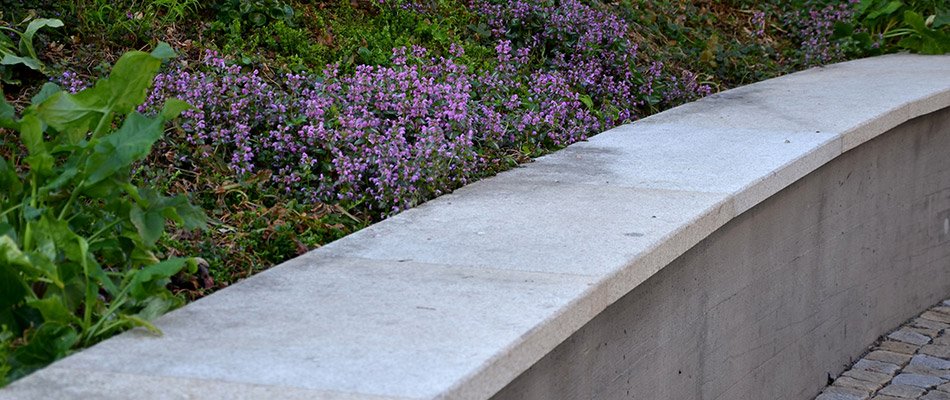 A grey seating wall installed along a landscape bed in Mishawaka, IN.