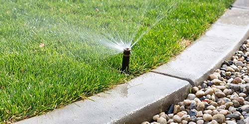 Sprinkler watering lawn near landscape walkway in Granger, IN.